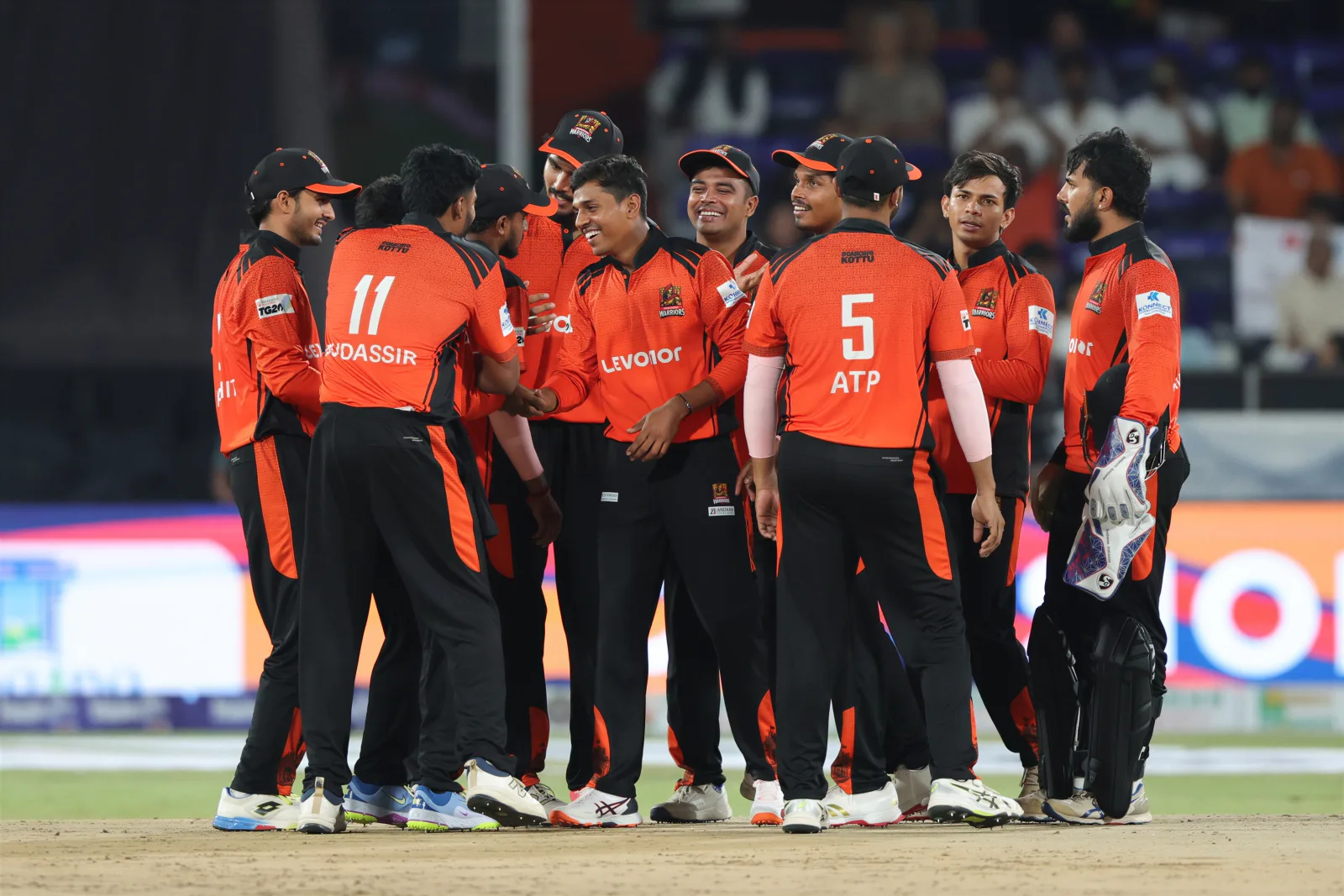 Cricket team huddle in orange and black kits