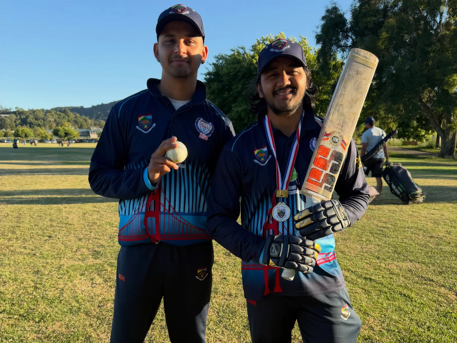 Two cricket players showing navy custom cricket jerseys
